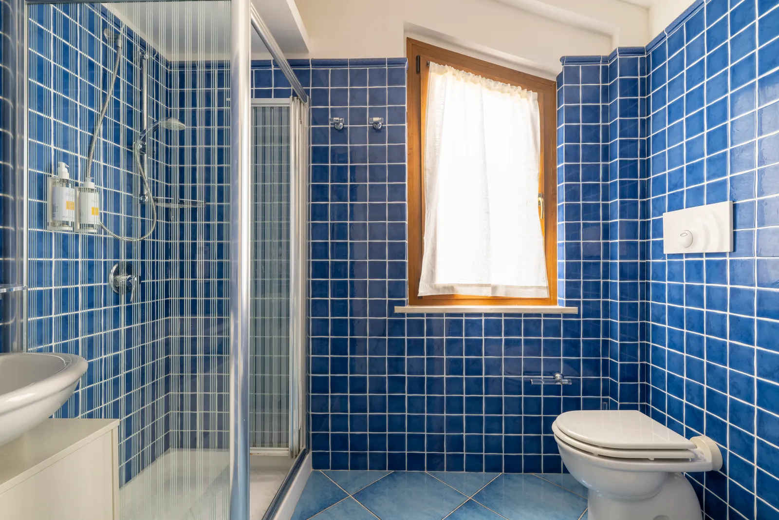 Bagno con doccia e piastrelle blu